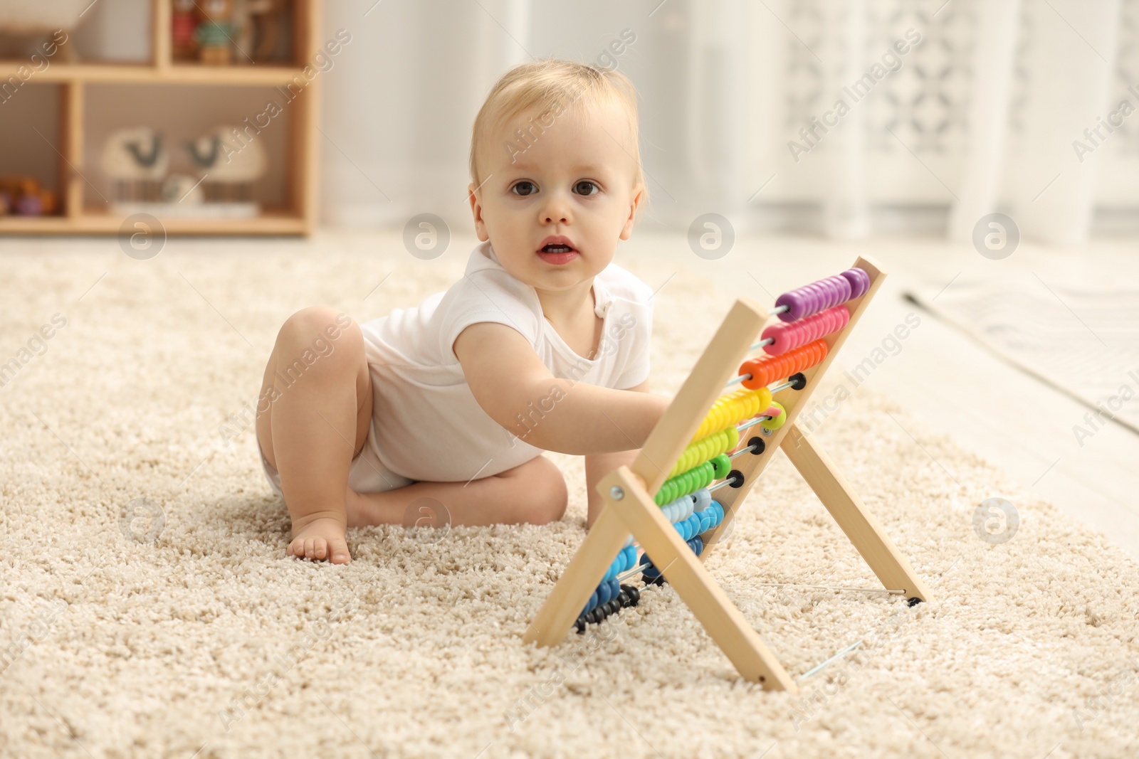 Photo of Children toys. Cute little boy playing with wooden abacus on rug at home