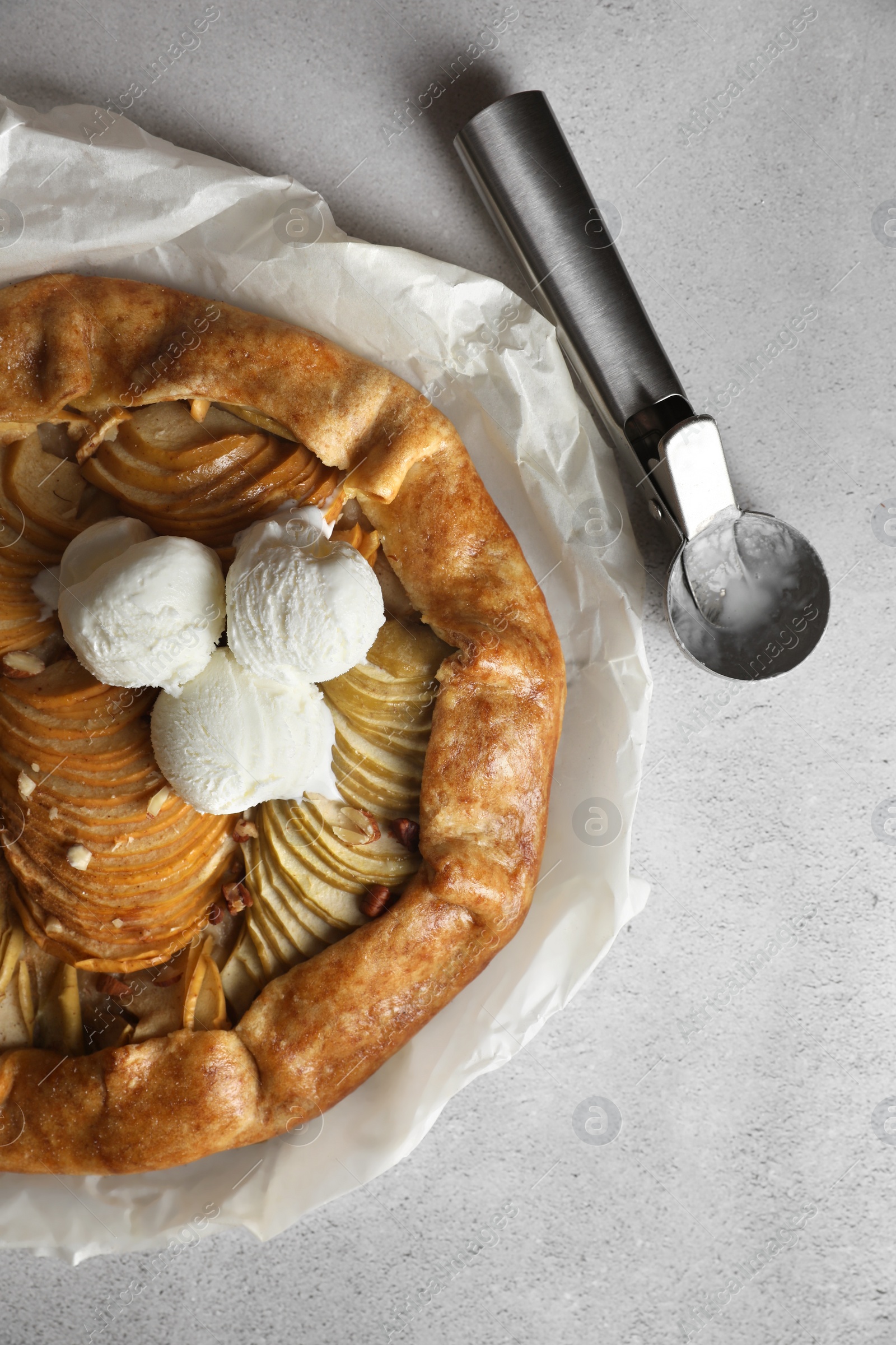 Photo of Delicious apple galette served with ice cream on light grey textured table, top view