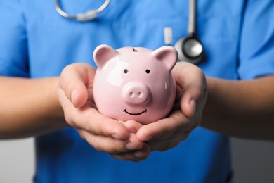Photo of Doctor holding piggy bank in hands, closeup. Medical insurance