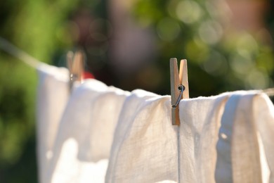 Washing line with drying shirt against blurred background, focus on clothespin