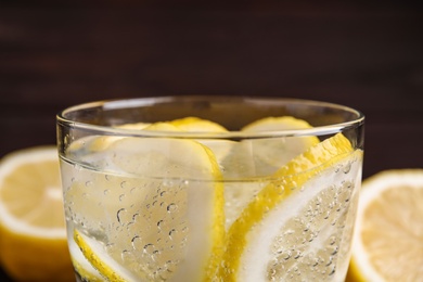 Photo of Soda water with lemon slices on dark background, closeup