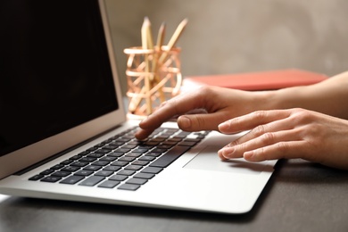 Woman using modern laptop at table, closeup