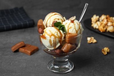 Delicious ice cream with caramel and sauce served on table