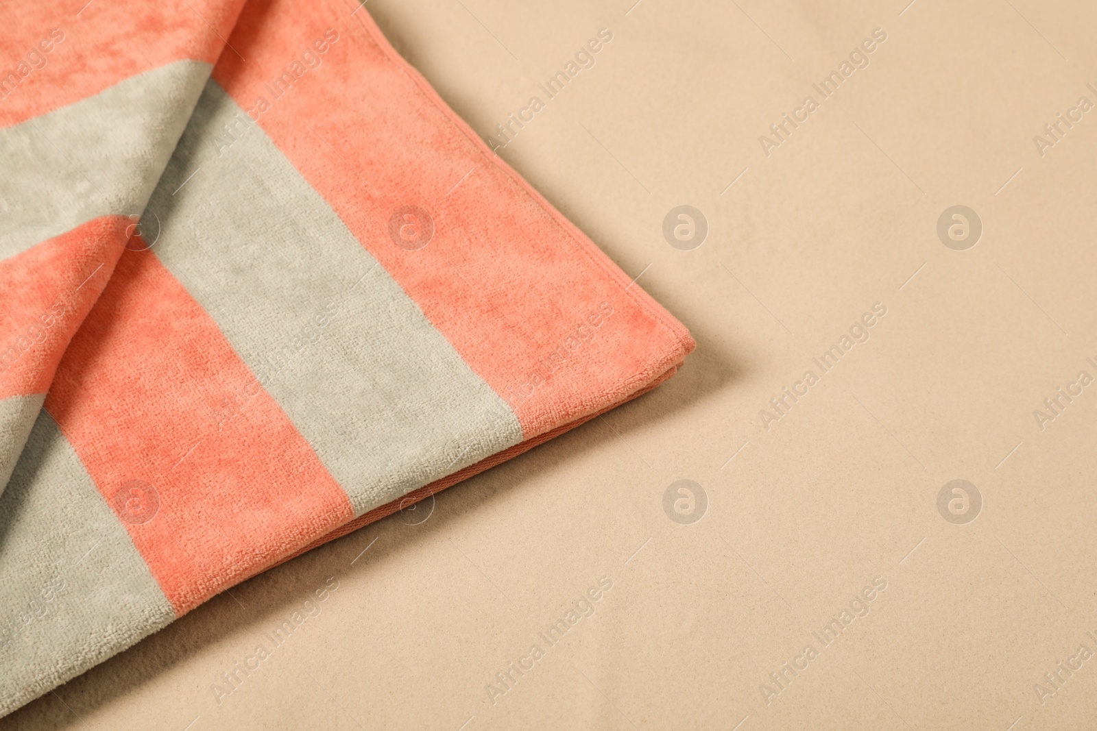 Photo of Striped soft beach towel on sand, closeup