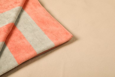 Photo of Striped soft beach towel on sand, closeup