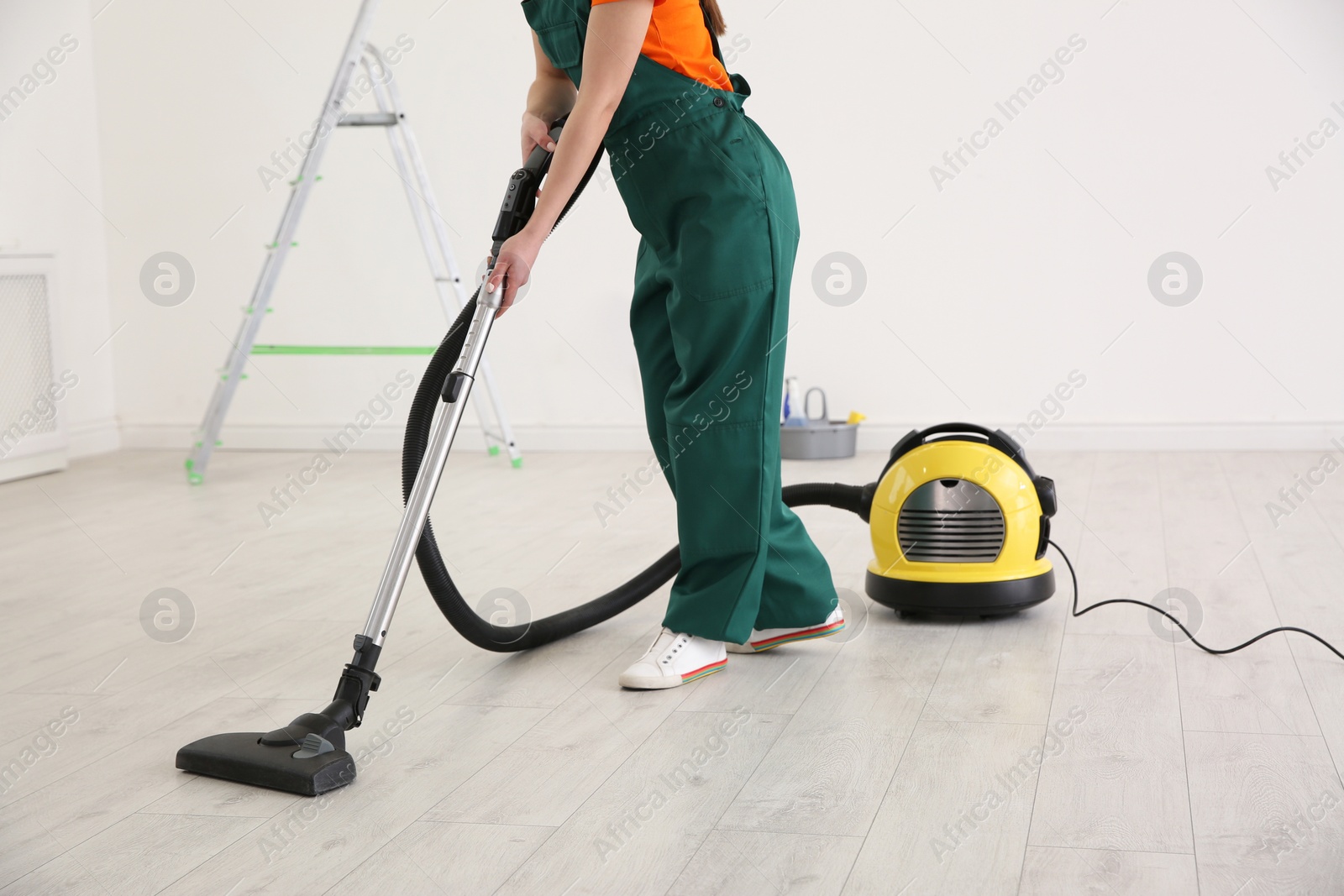 Photo of Professional young janitor vacuuming indoors. Cleaning service