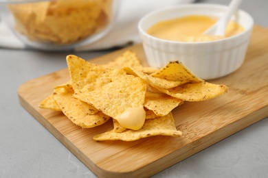 Board with Mexican nacho chips and sauce on grey table, closeup