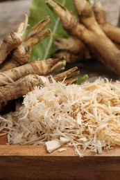 Photo of Grated horseradish and roots on table, closeup