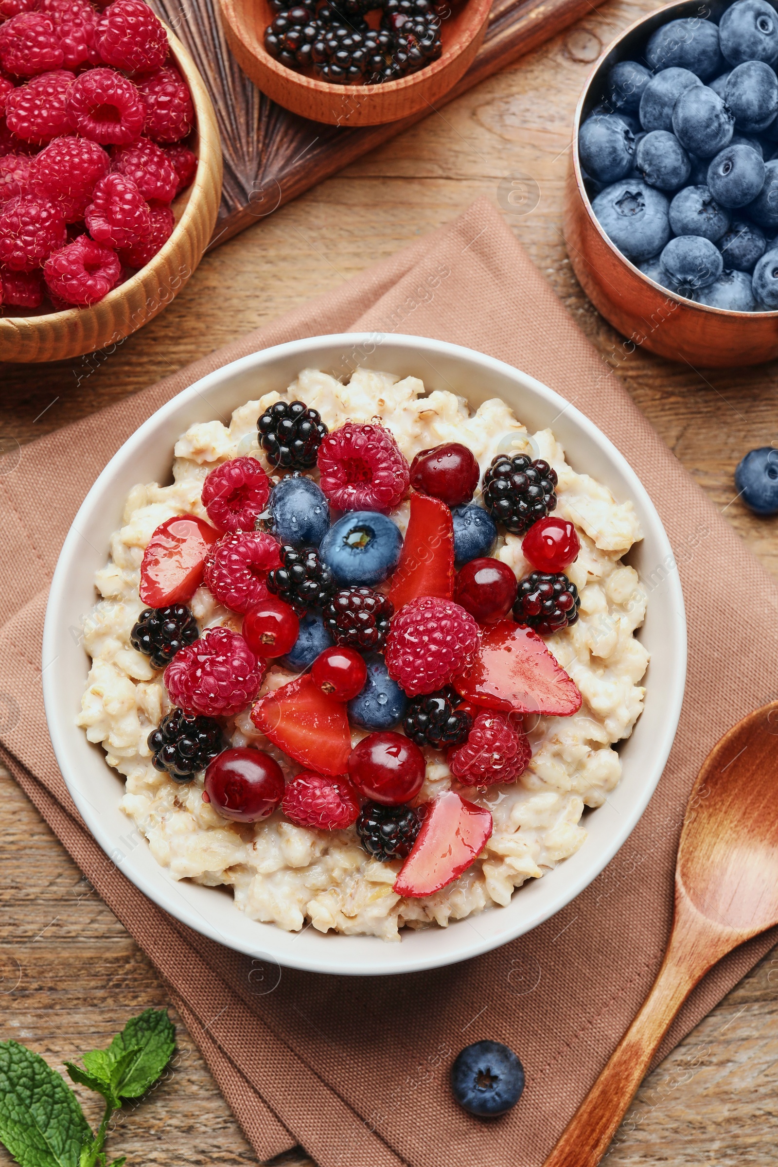 Photo of Flat lay composition with tasty oatmeal porridge and ingredients served on wooden table. Healthy meal