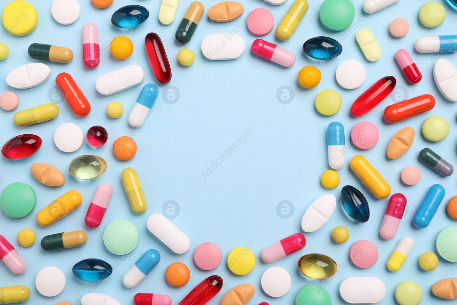 Photo of Frame made of many different pills on light blue background, flat lay. Space for text