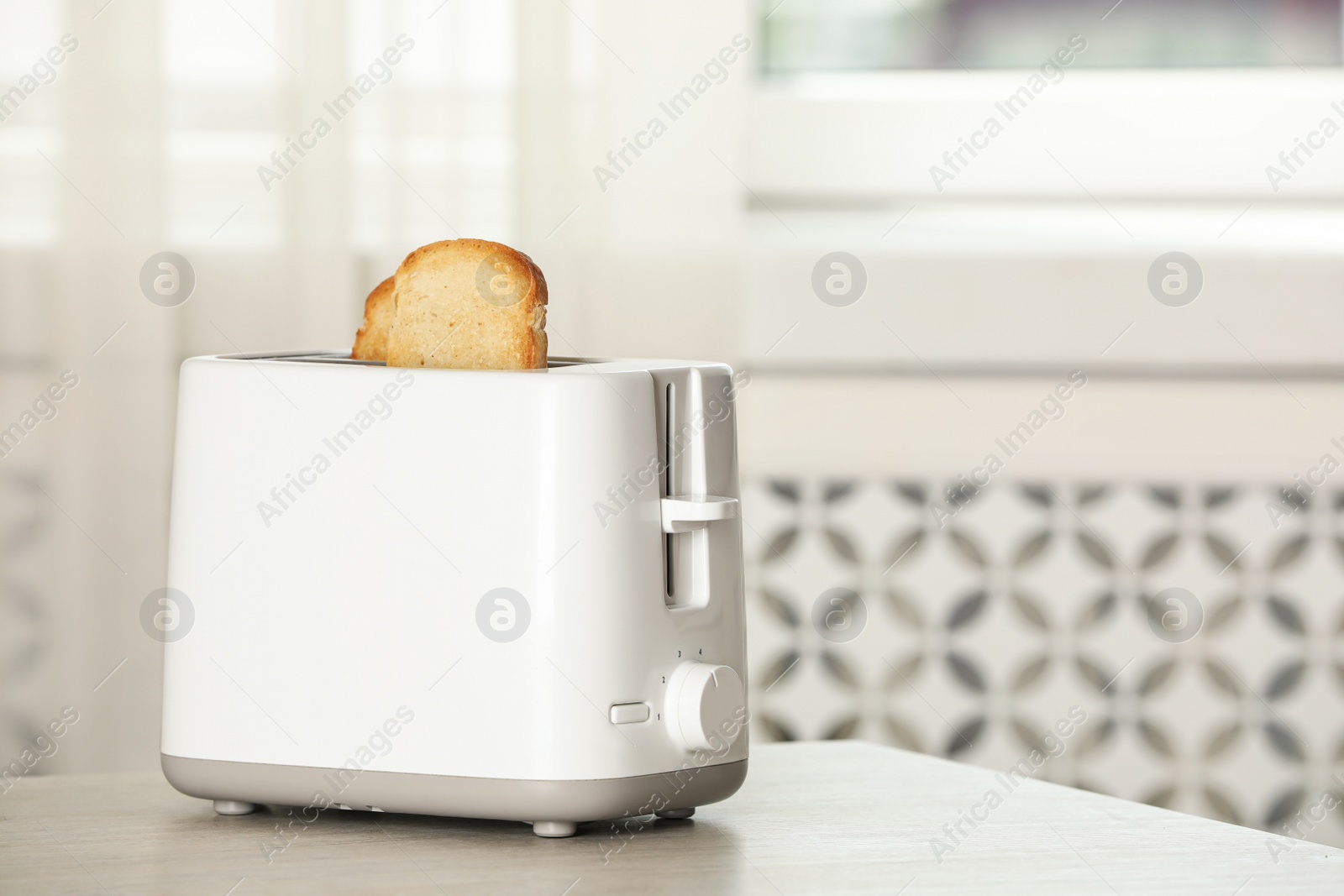 Photo of Electric toaster with bread slices on wooden table. Space for text