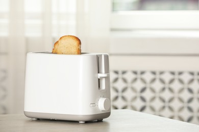 Photo of Electric toaster with bread slices on wooden table. Space for text