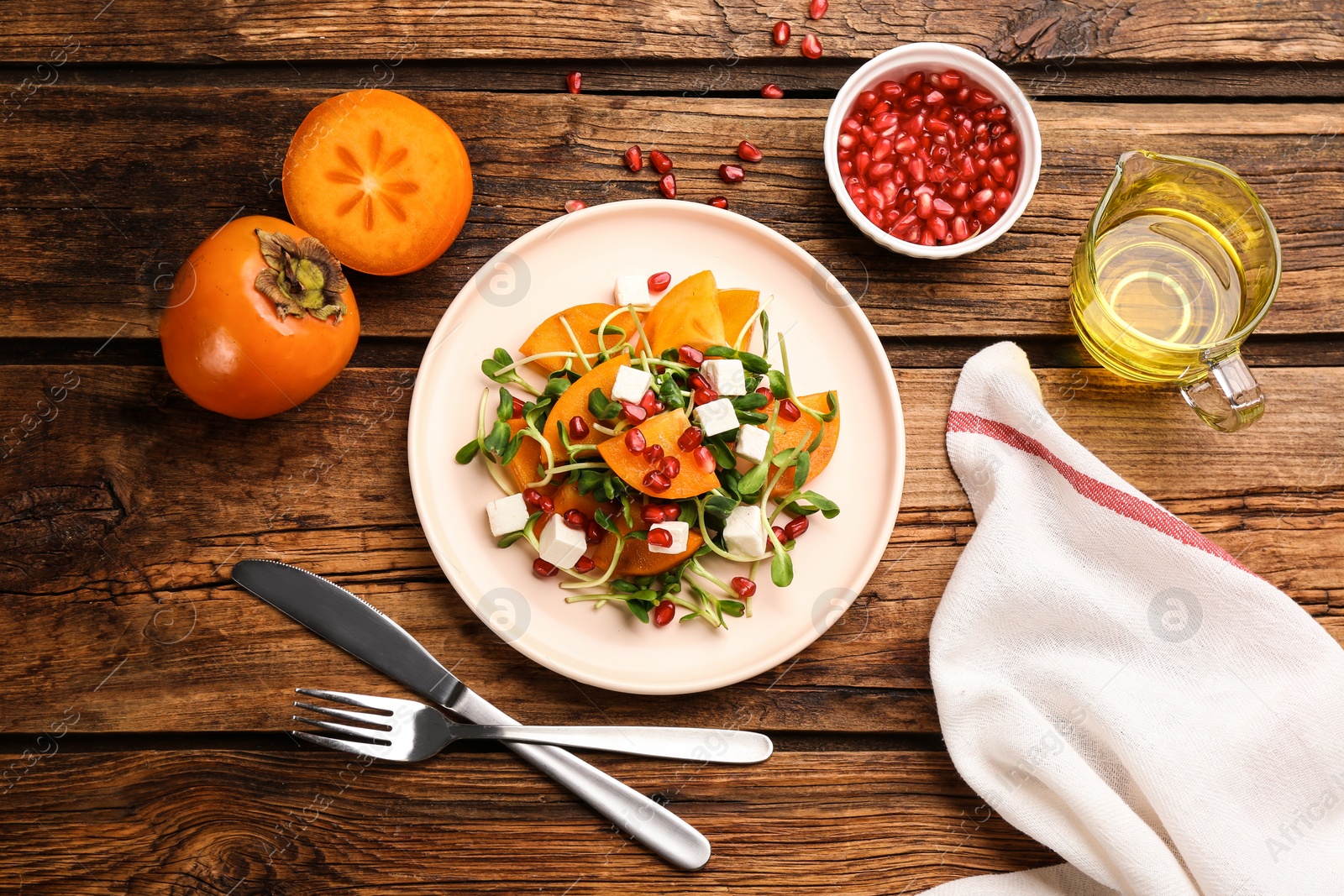 Photo of Delicious persimmon salad served on wooden table, flat lay