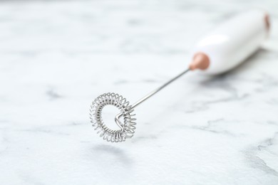 Photo of Milk frother wand on white marble table, closeup