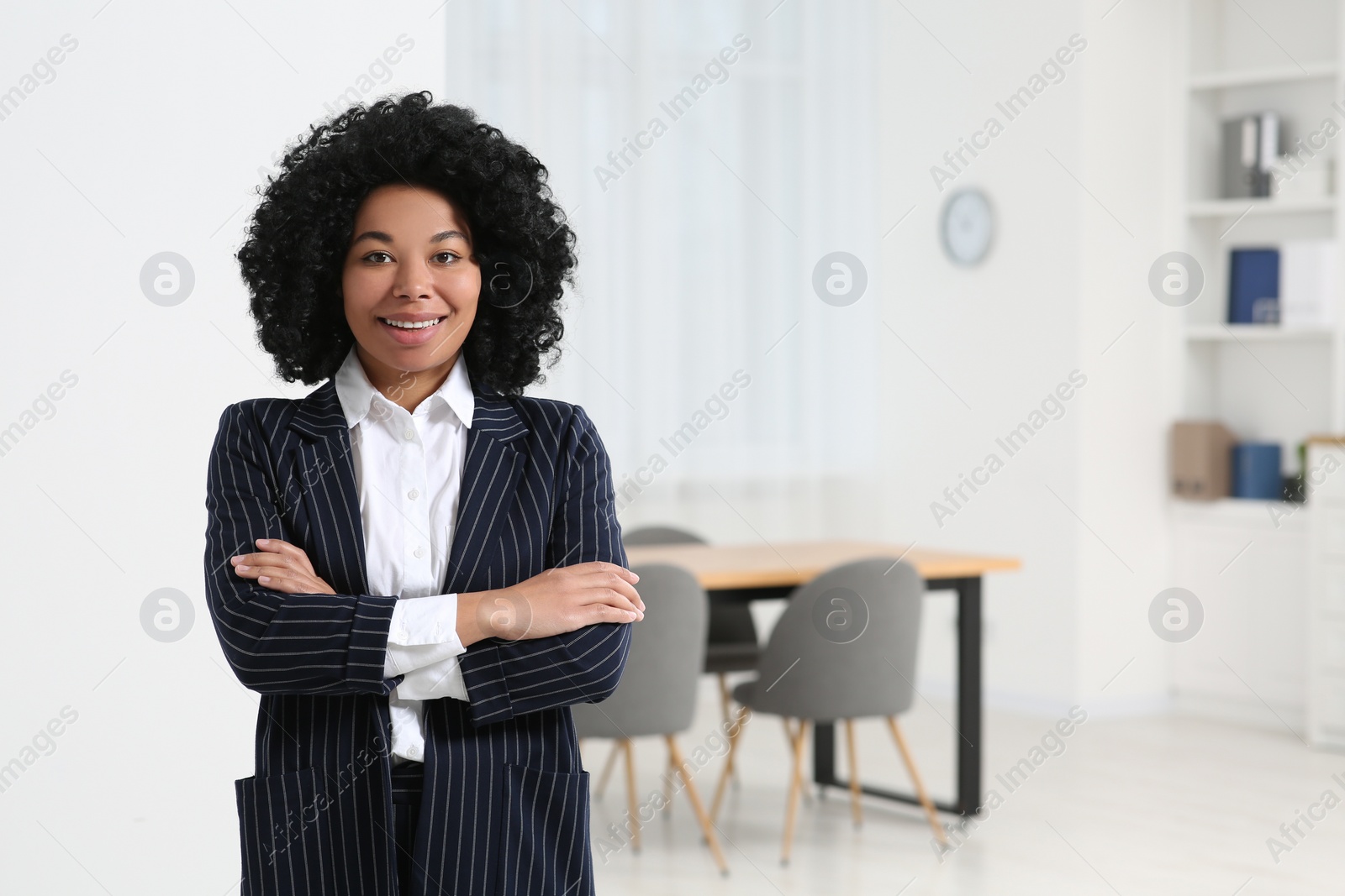 Photo of Smiling young businesswoman in modern office. Space for text