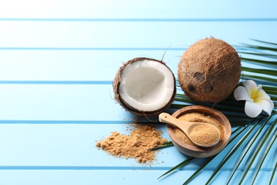 Photo of Coconut sugar, palm leaves, fruits and flower on light blue wooden table. Space for text