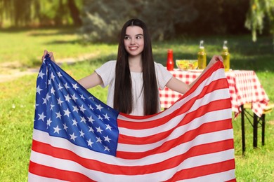 Image of 4th of July - Independence day of America. Happy girl with national flag of United States having picnic in park