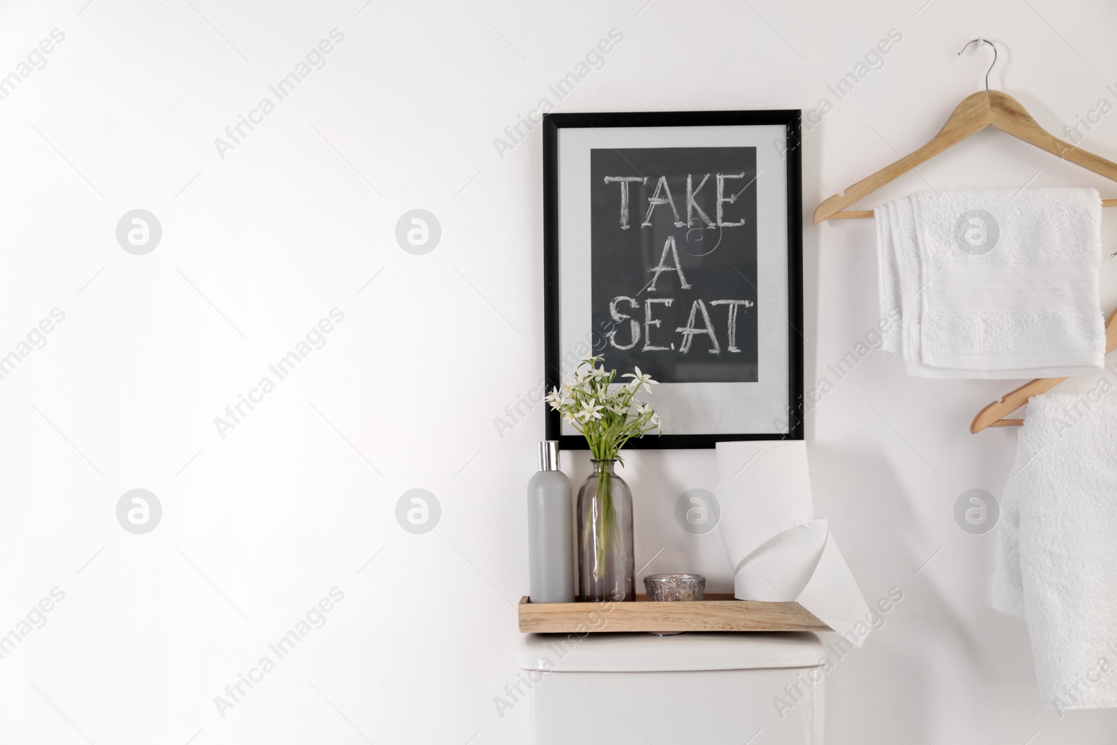 Photo of Decor elements, necessities and toilet bowl near white wall, space for text. Bathroom interior