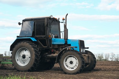 Photo of Tractor in field on spring day. Agricultural industry