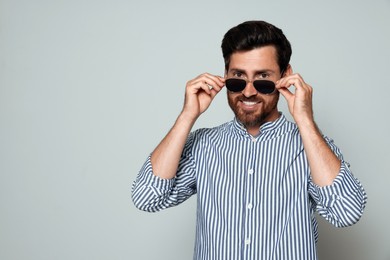 Portrait of smiling bearded man with sunglasses on grey background. Space for text
