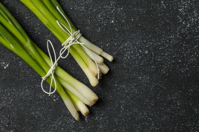 Photo of Bunch of fresh green onion on black table, flat lay. Space for text