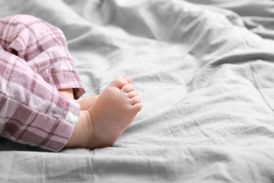 Photo of Little baby in pajamas on bed, closeup. Space for text