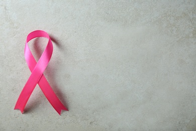 Pink ribbon and space for text on gray background, top view. Breast cancer awareness concept