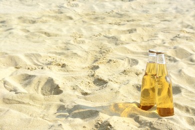 Photo of Bottles of cold beer on sandy beach near sea, space for text