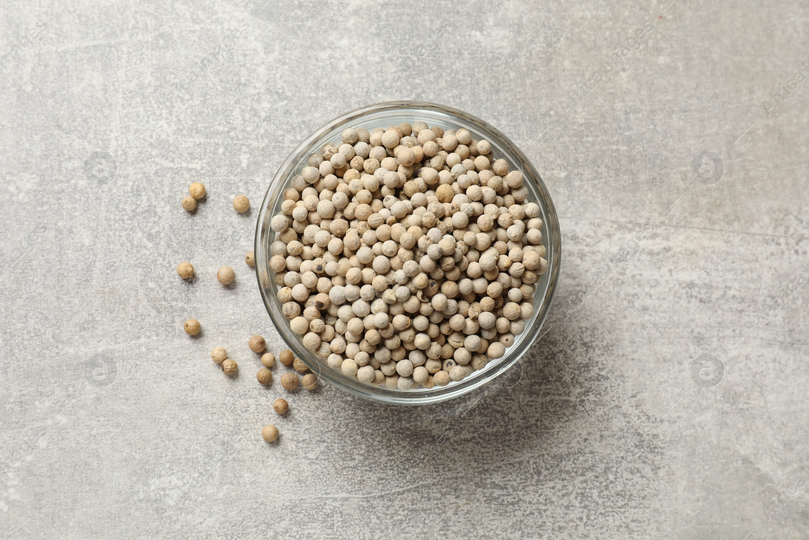 Photo of Aromatic spice. White pepper in bowl on light grey table, top view