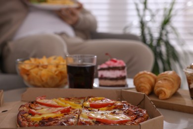 Photo of Overweight man at home, focus on pizza