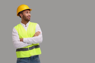 Engineer in hard hat on grey background, space for text