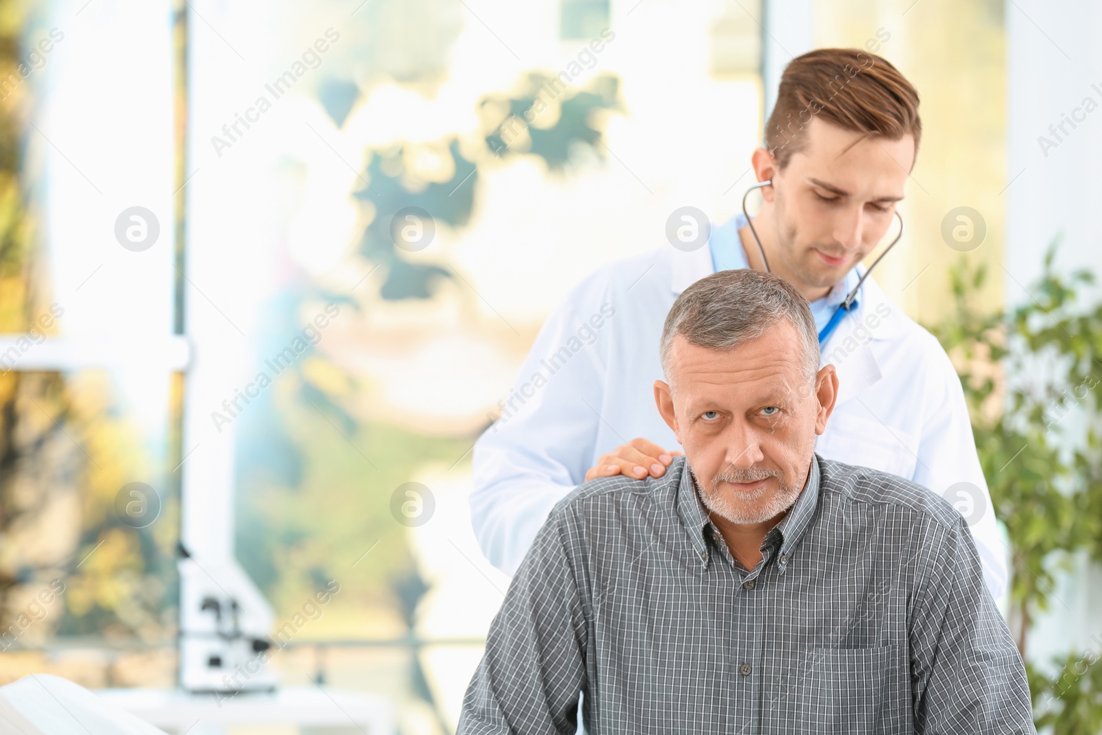 Photo of Doctor examining mature patient with stethoscope in hospital. Space for text