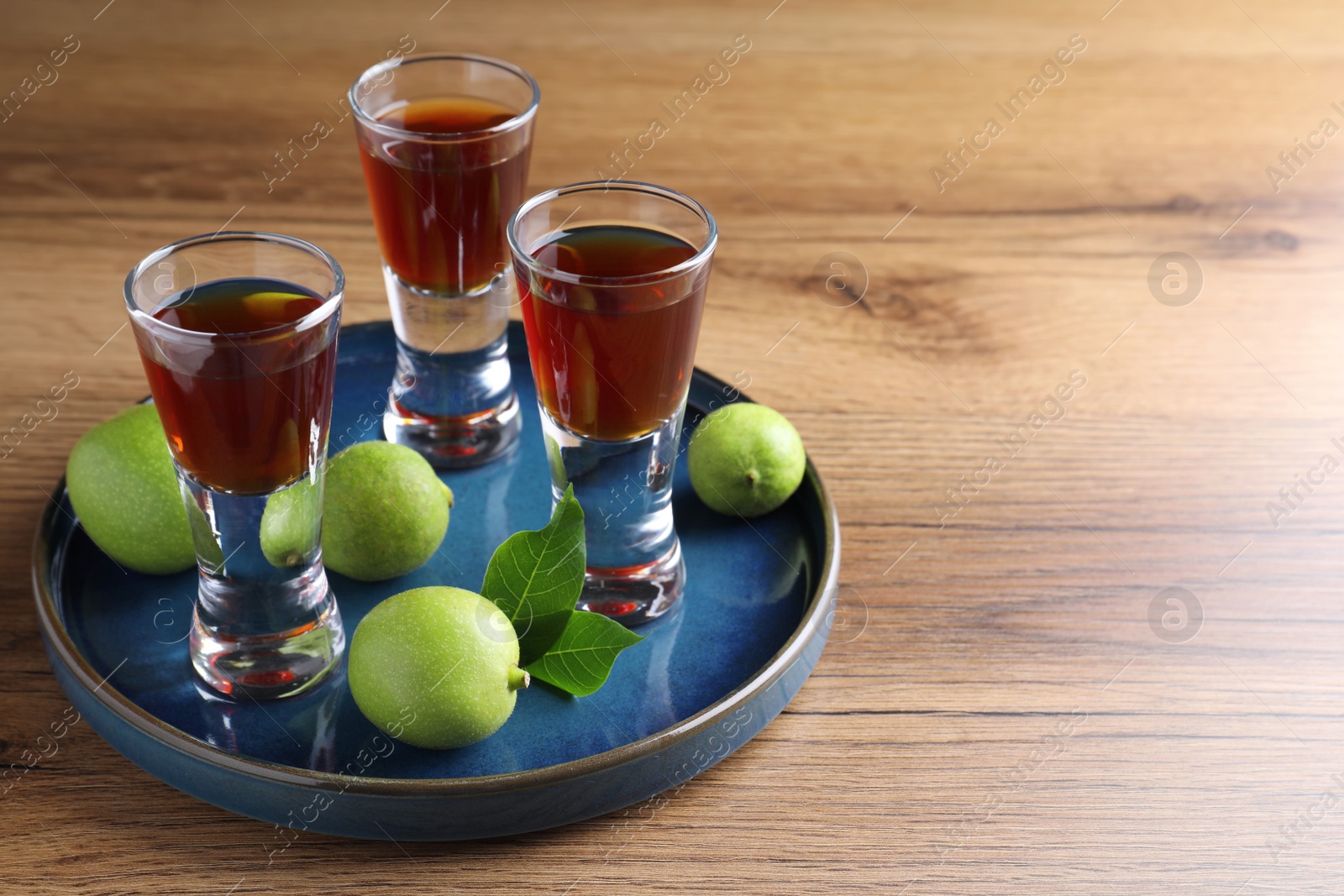 Photo of Delicious liqueur and green walnuts on wooden table. Space for text