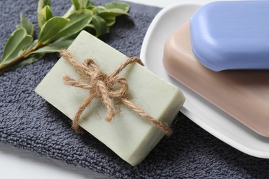 Photo of Different soap bars, plant and terry towel on table, closeup