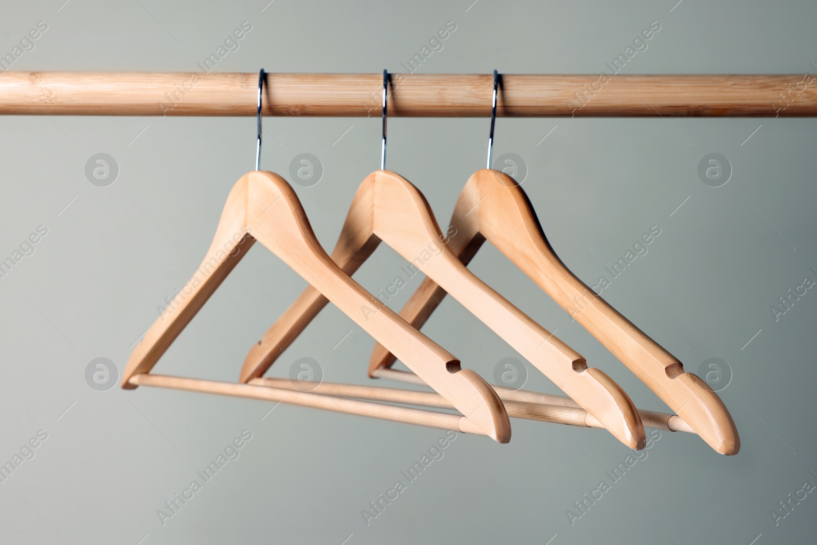 Photo of Clothes hangers on wooden rail against beige background