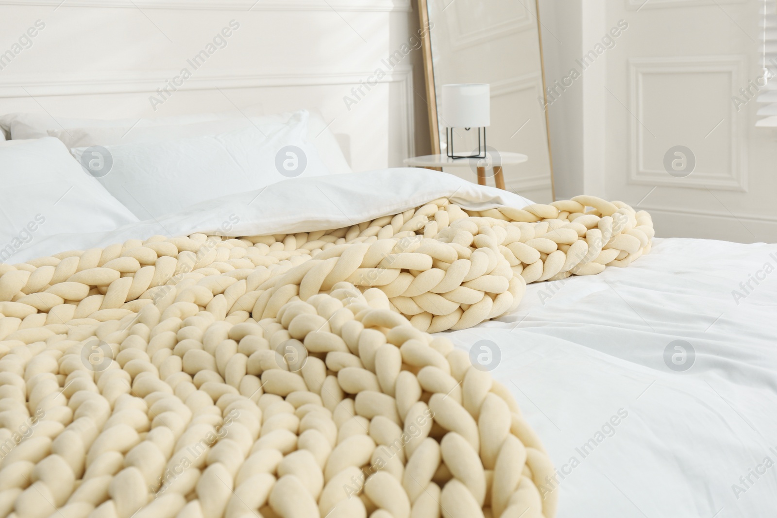 Photo of Soft chunky knit blanket on bed in light room