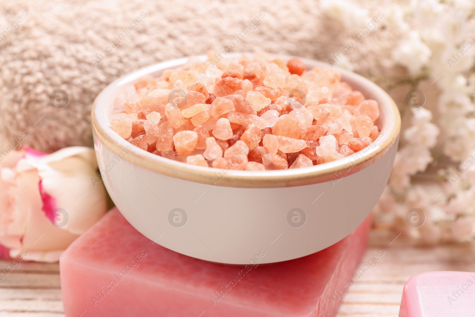 Photo of Bowl with sea salt and soap bar on white wooden table, closeup