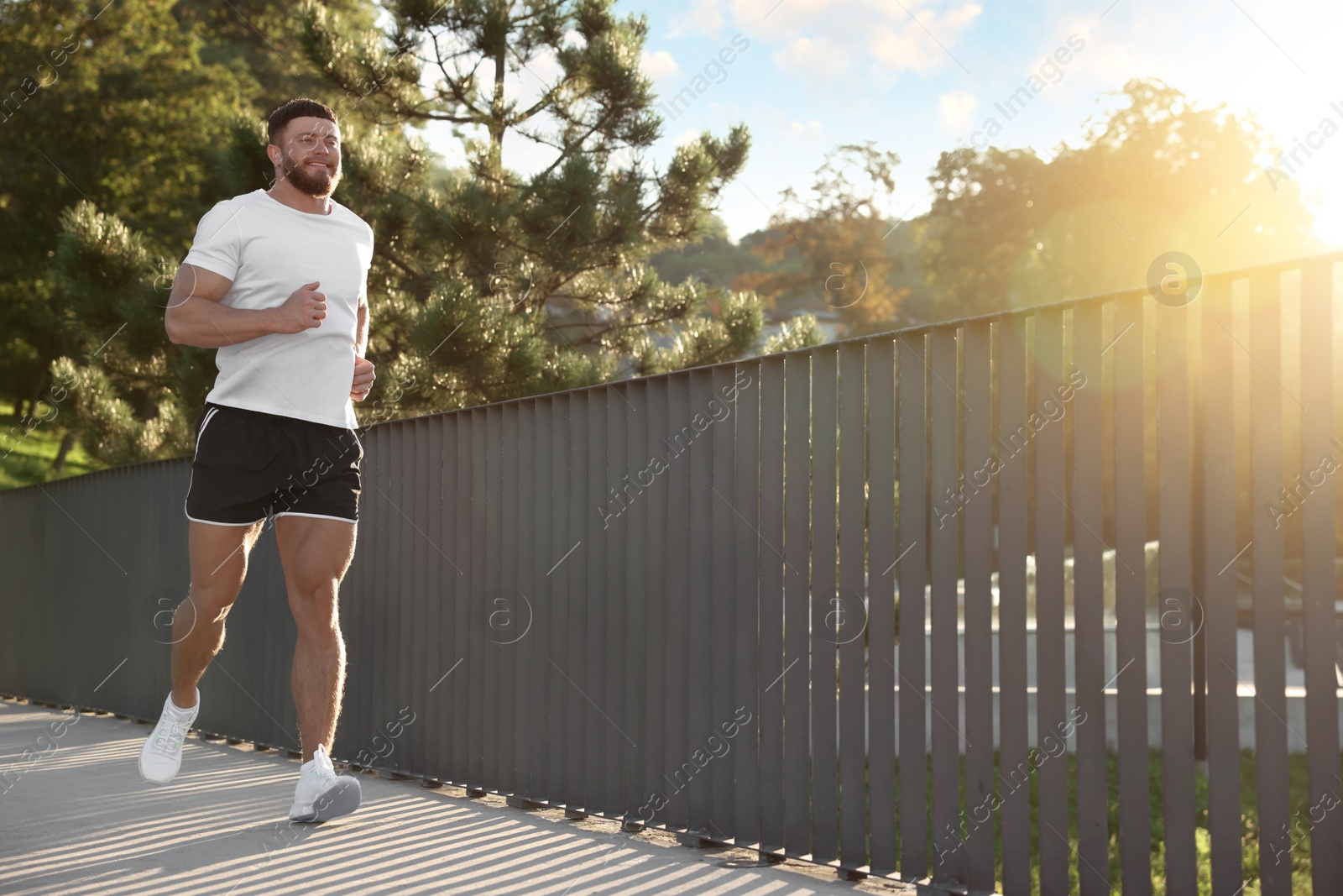 Photo of Young man running outdoors on sunny day. Space for text