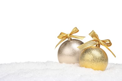 Photo of Beautiful golden Christmas balls with bows on snow against white background