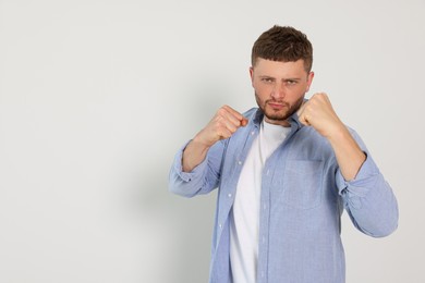 Young man ready to fight on white background, space for text