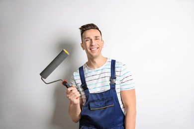 Photo of Young male decorator with paint roller on white background