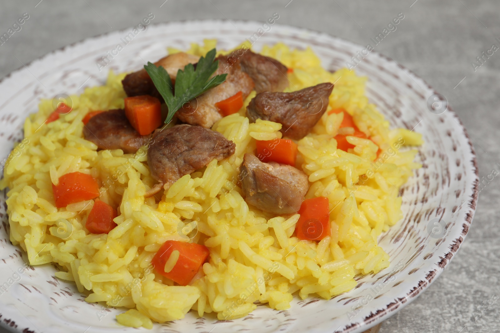 Photo of Delicious pilaf with meat served on light grey table, closeup