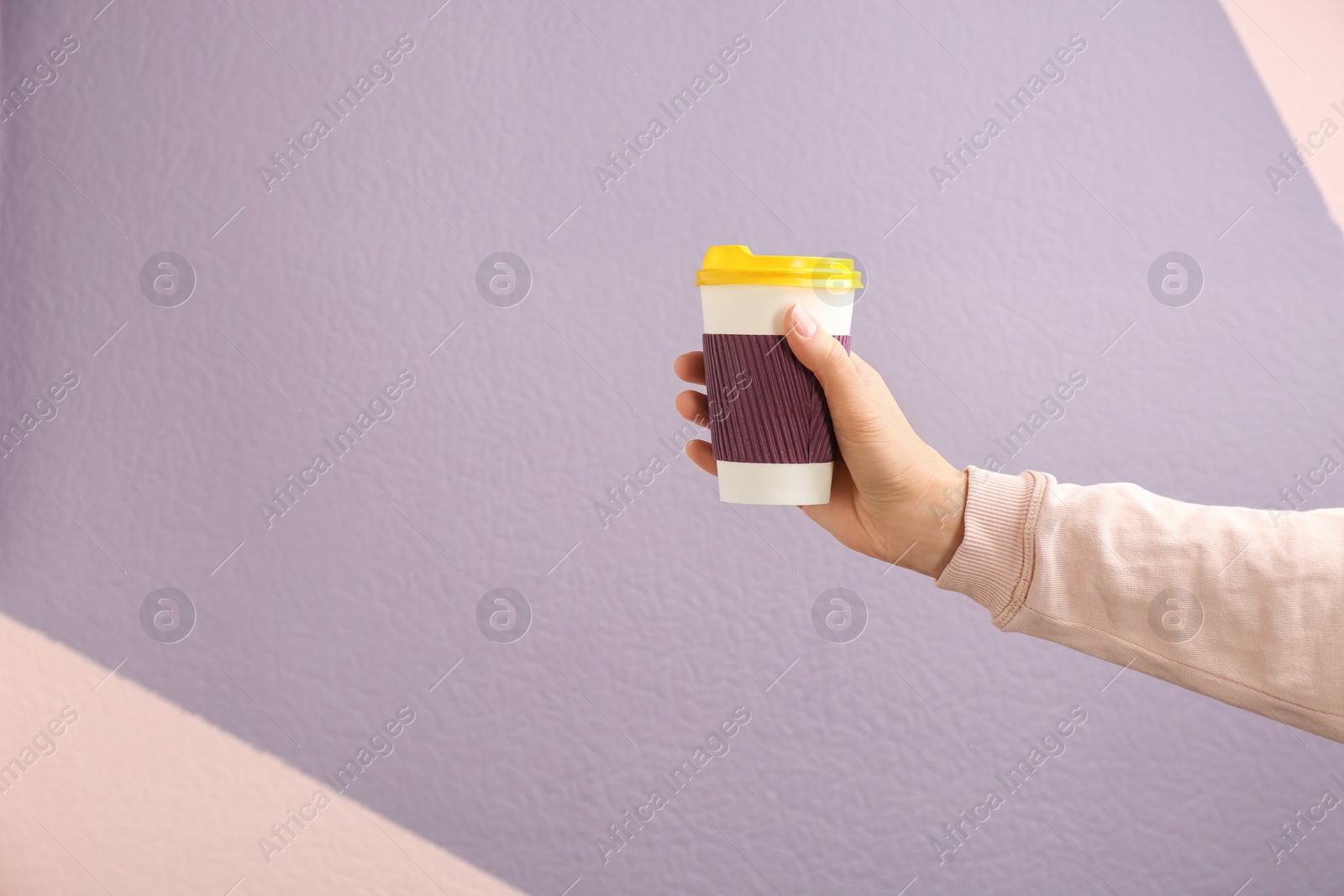 Photo of Woman holding takeaway paper coffee cup on color background. Space for text