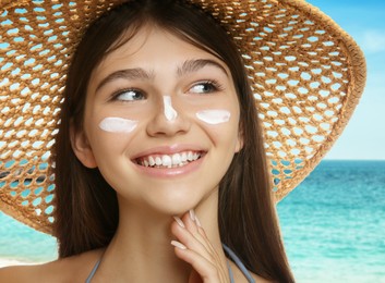Image of Teenage girl with sun protection cream on her face near sea, closeup