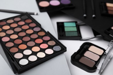 Photo of Many different eye shadow palettes on colorful background