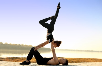 Beautiful young couple practicing dance moves near river at sunset