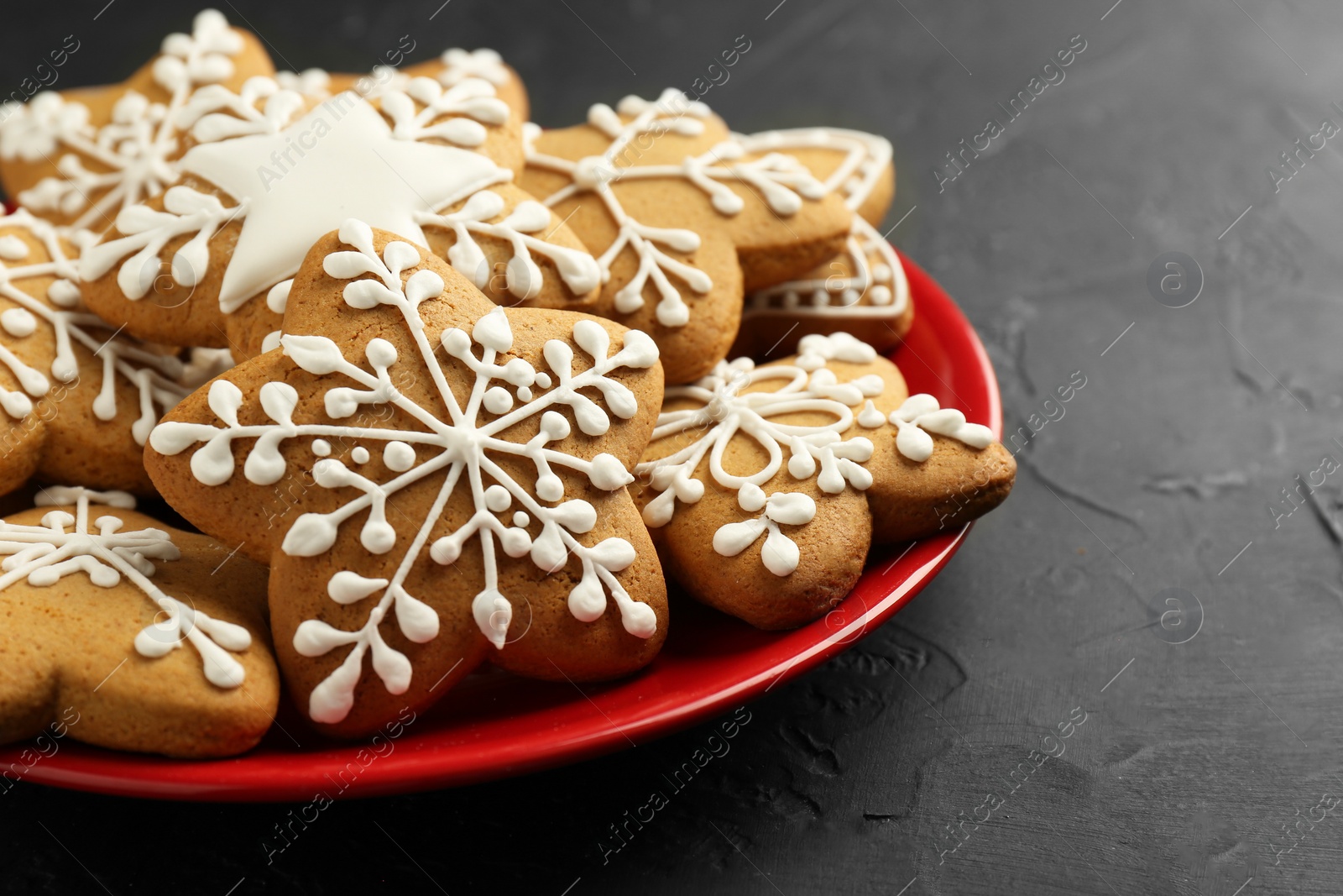 Photo of Tasty Christmas cookies with icing on black table, closeup. Space for text