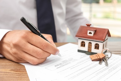 Photo of Man signing document at table in real estate agent's office