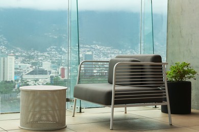 Coffee table and sofa against picturesque landscape of city in cafe