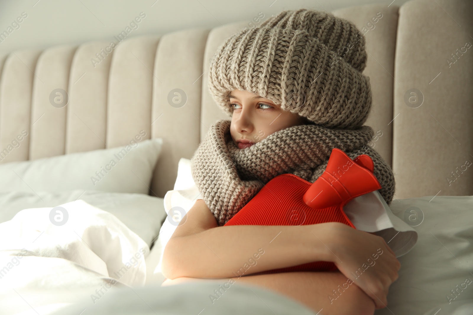 Photo of Ill girl with hot water bottle suffering from cold in bed at home
